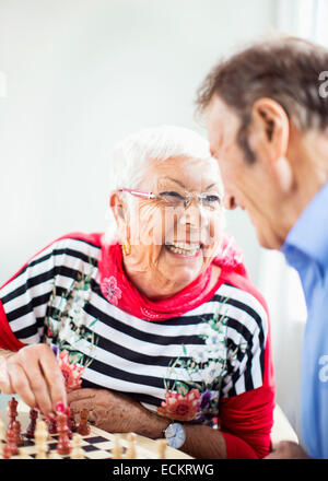 Gerne älteres paar Blick auf einander beim Schachspielen im Pflegeheim Stockfoto