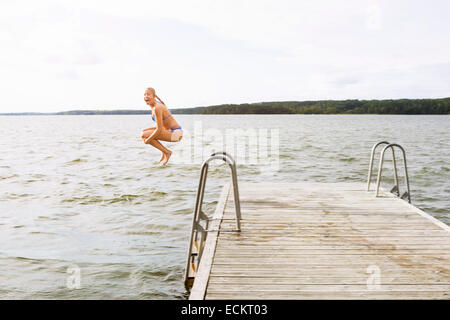 Voller Länge Seitenansicht erregte Frau springen in See Stockfoto