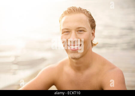 Porträt der glückliche junge Frau sitzt am Seeufer Stockfoto