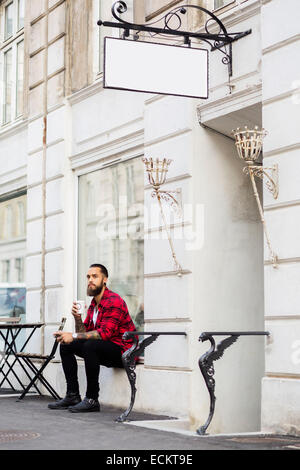 Kaffeetrinken beim Sitzen außen Candy Shop Besitzer Stockfoto