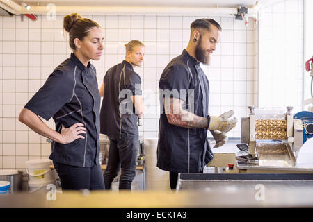 Arbeitnehmer, die betrachten Bonbonmaschine im store Stockfoto