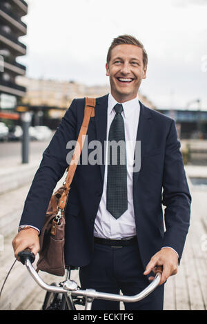 Lächelnde Geschäftsmann stehend mit dem Fahrrad in die Stadt Stockfoto