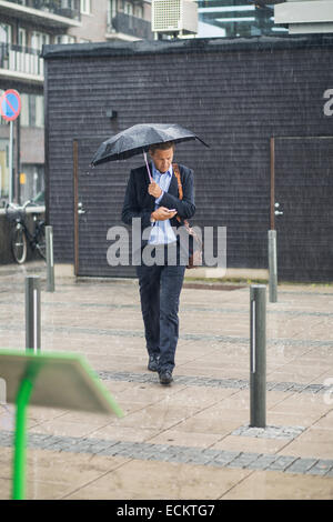 Gesamte Länge der Geschäftsmann auf Bürgersteig während der Regenzeit Wandern Stockfoto