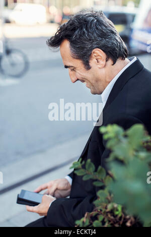 Glücklich Kaufmann mit Handy auf Bürgersteig durch Stadtstraße Stockfoto