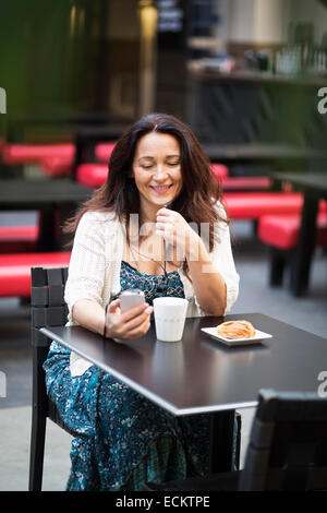 Frau mit Smartphone im Café im freien Stockfoto