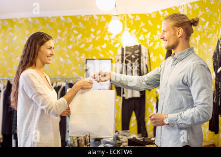 Glückliche Kundin die Einkaufstasche von Verkäufer an der Kasse in boutique Stockfoto