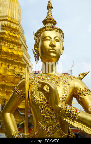 Goldene Kinnon (Kinnaree) Statue hält eine Rose mit einem goldenen Phra Chedi im Hintergrund am Grand Palace Bangkok Thailand Stockfoto