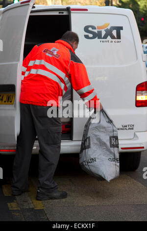 Wimbledon, London, UK. 16 Dez, 2014. Ein Royal Mail Arbeiter trägt Weihnachtspost in Beuteln aus einer Postfiliale in Wimbledon. mehr Warteschlangen bei der Post als Menschen die Weihnachten post Frist zu bekommen. Die längere Warteschlangen ist parlty durch die Schließung von Postfilialen im gesamten Vereinigten Königreich Kredit verursacht: Amer ghazzal/alamy leben Nachrichten Stockfoto