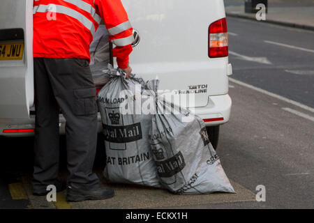 Wimbledon, London, UK. 16 Dez, 2014. Ein Royal Mail Arbeiter trägt Weihnachtspost in Beuteln aus einer Postfiliale in Wimbledon. mehr Warteschlangen bei der Post als Menschen die Weihnachten post Frist zu bekommen. Die längere Warteschlangen ist parlty durch die Schließung von Postfilialen im gesamten Vereinigten Königreich Kredit verursacht: Amer ghazzal/alamy leben Nachrichten Stockfoto