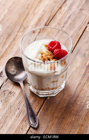 Glas des leckeren Joghurt Müsli mit Himbeeren auf hölzernen Hintergrund Stockfoto