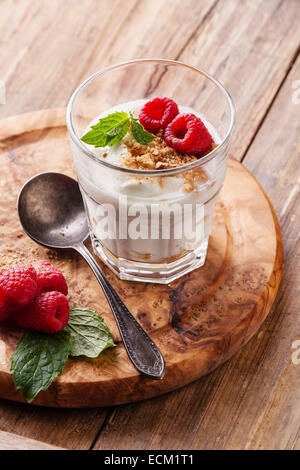 Glas des leckeren Joghurt Müsli mit Himbeeren auf hölzernen Hintergrund