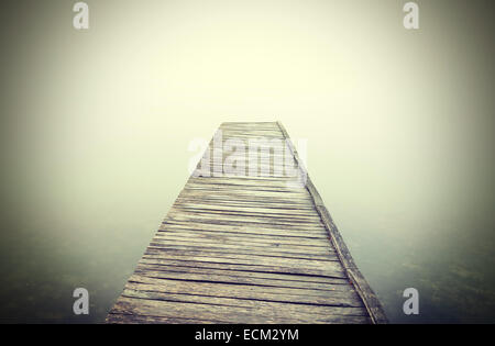 Retro-gefilterte Bild der alten hölzernen Pier in dichtem Nebel. Stockfoto