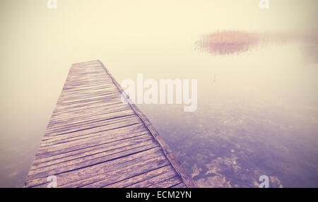 Retro-gefilterte Bild der alten hölzernen Pier in dichtem Nebel. Stockfoto