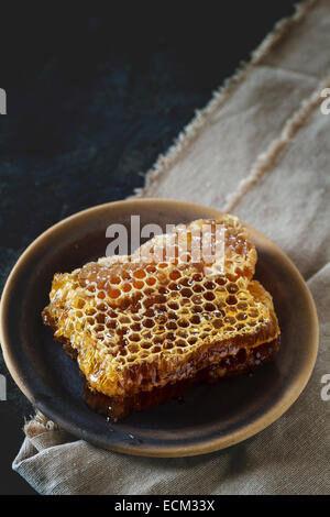 Bienenwabe auf Keramikplatte über alten Holztisch. Stockfoto