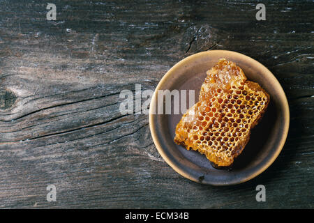 Bienenwabe auf Keramikplatte über alten Holztisch. Ansicht von oben. Stockfoto