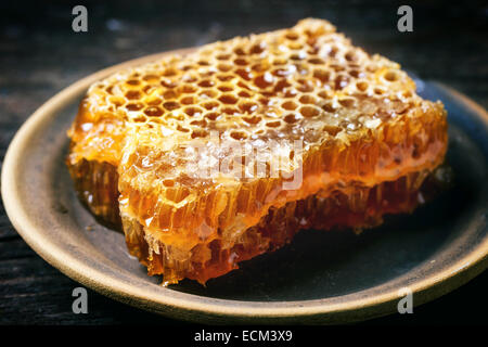 Clode, Honigwabe auf Keramikplatte über alten Holztisch. Stockfoto