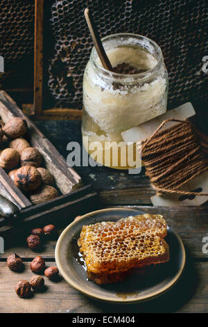 Frischen Waben mit jar von alten Honig und Mischung von Nüssen über alten Holztisch. Stockfoto