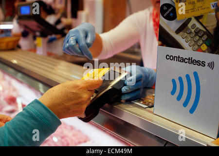 Eine Frau zahlt für eine Metzgerei mit einem kontaktlosen Kreditkarten-System in Mallorca, Spanien Stockfoto