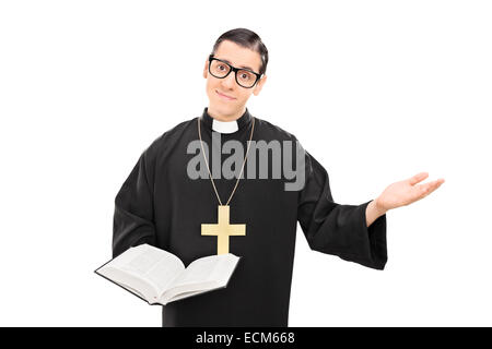 Junge katholische Priester hält eine Bibel und Gestikulieren mit seiner Hand isoliert auf weißem Hintergrund Stockfoto