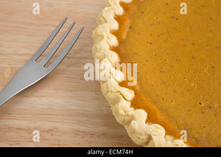 Eine Nahaufnahme von einem Kürbiskuchen auf einer hölzernen Tischplatte mit einer Gabel. Stockfoto