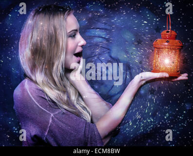 Closeup Portrait von netten blonden Mädchen mit Blick auf rot leuchtende Laterne in der Hand dunkle Sternennacht, Weihnachten magische Überraschung Stockfoto