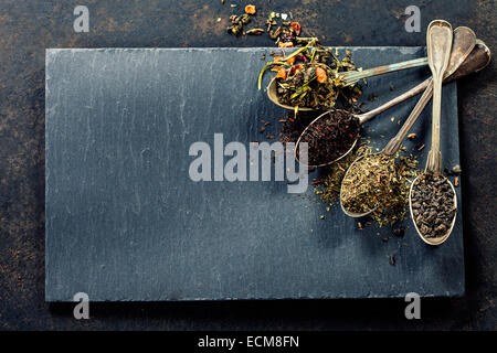 Tee-Komposition mit verschiedenen Arten von Tee und alte Löffel auf dunklem Hintergrund Stockfoto