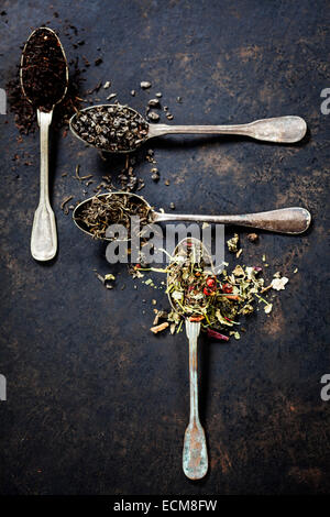 Tee-Komposition mit verschiedenen Arten von Tee und alte Löffel auf dunklem Hintergrund Stockfoto