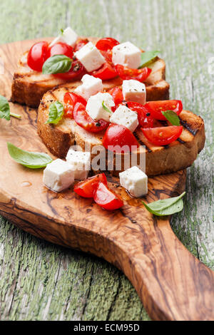 Bruschetta mit Tomaten, Basilikum und Käse auf gegrilltem knusprigem Brot Stockfoto