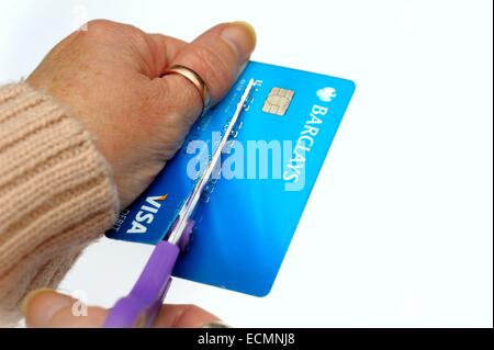 Eine Frau Zerschneiden einer Visa Debit-Karte auf ein weißes Studio-Hintergrund England UK Stockfoto