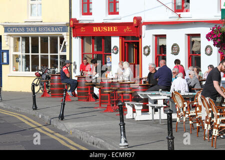 Baltimore West Cork County Cork in Irland mit Menschen an Tischen, die außerhalb einer öffentlichen Haus trinken sitzen und an der Bushe Bar essen. Stockfoto