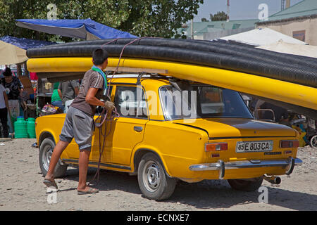 Usbekische jungen Befestigung große Rohre im oberen Teil alte Trabant in Usbekistan Stockfoto