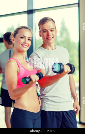 lächelnde junge Frau mit personal Trainer im Fitness-Studio Stockfoto