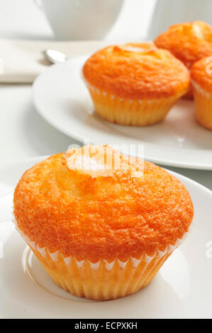 eine Platte mit einigen Magdalenas, typisch spanische schlicht Muffins und eine Tasse Kaffee im Hintergrund auf einem gedeckten Tisch Stockfoto