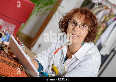 Schneiderin Blick auf eine digital-Tablette in seiner Werkstatt Stockfoto
