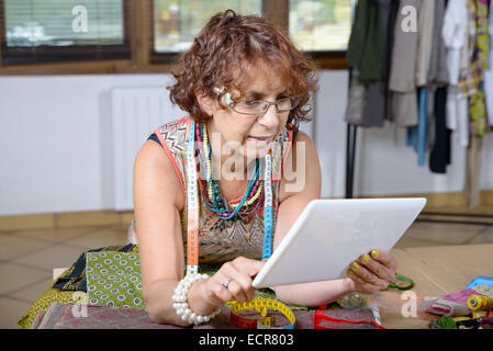 Schneiderin Blick auf eine digital-Tablette in seiner Werkstatt Stockfoto