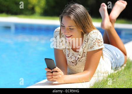 Teenager-Mädchen mit einem Smartphone ruht auf einer Pool-Seite mit einem blauen Wasser Hintergrund