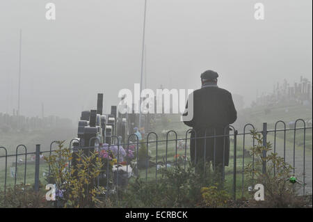 Mann, der betet in Nebel gehüllt Friedhof.  Foto © George Sweeney/Alamy Stockfoto