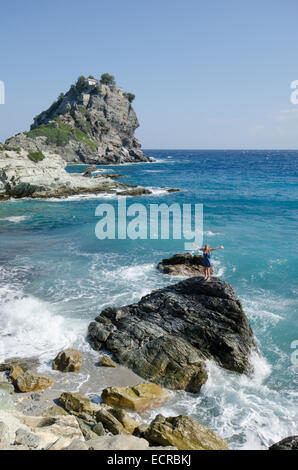 Frau am Strand oben auf Felsen vor Mamma Mia Kapelle Agios Ioannis, Skopelos, Griechenland. Oktober. Stockfoto