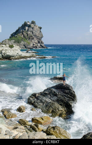 Frau am Strand oben auf Felsen vor Mamma Mia Kapelle Agios Ioannis, Skopelos, Griechenland. Oktober. Stockfoto