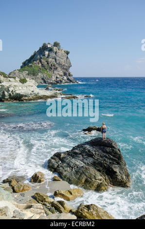 Frau am Strand oben auf Felsen vor Mamma Mia Kapelle Agios Ioannis, Skopelos, Griechenland. Oktober. Stockfoto