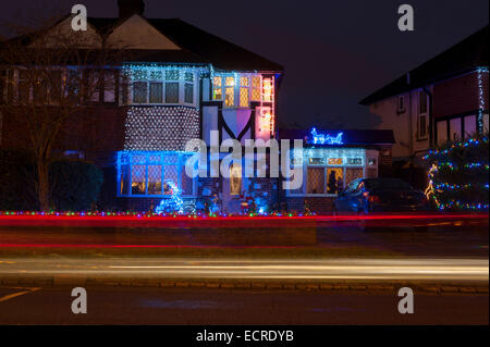 Unteren Morden, Surrey, UK. 18. Dezember 2014. Bewohner der unteren Morden Lane schmücken das Äußere ihres Hauses mit Weihnachtsbeleuchtung und Skulpturen, Zeichnung Massen von Touristen jährlich. Vorbeifahrende Autos schaffen zusätzliche Lichtspuren in dieser langen Belichtungszeit. Bildnachweis: Malcolm Park Leitartikel/Alamy Live-Nachrichten Stockfoto