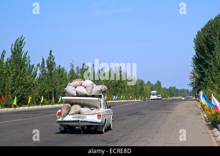 Auto mit großen Säcken gelagert auf Dach und Kofferraum fahren entlang der Autobahn in Usbekistan überlastet Stockfoto