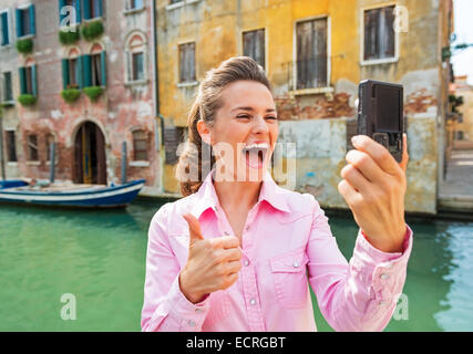 Glückliche junge Frau zeigt Daumen oben und Selfie in Venedig, Italien Stockfoto