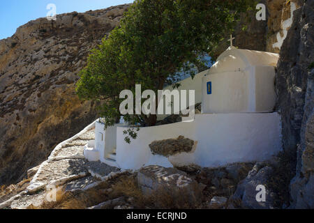 Weiß lackiertes Kapelle unter Felswand mit Bäumen und sonnigen Schritte Stockfoto