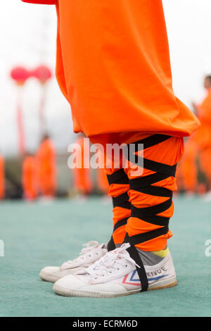 Shaolin Kung Fu Schüler tragen Feiyue Schuhe und orange Uniforml in DengFeng, Henan, China 2014 Stockfoto