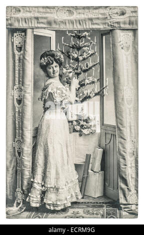 junge Frau mit Weihnachtsbaum und Geschenke. antikes Bild mit original Kratzer, Filmkorn und Unschärfe Stockfoto