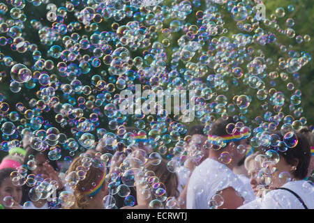 Glückliche Farbe führen Sie die Teilnehmer durch eine bunte Wolke von Seifenblasen umgeben Stockfoto