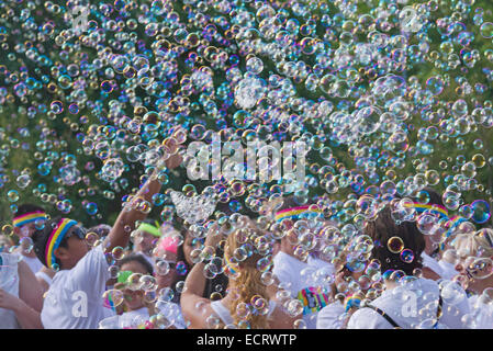 Glückliche Farbe führen Sie die Teilnehmer durch eine bunte Wolke von Seifenblasen umgeben Stockfoto