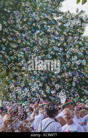 Glückliche Farbe führen Sie die Teilnehmer durch eine bunte Wolke von Seifenblasen umgeben Stockfoto