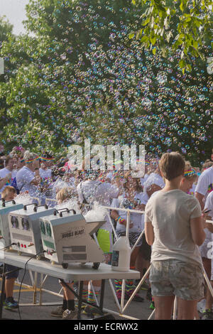 Happy Color Run Teilnehmer sind umgeben von einer bunten Wolke aus Seifenblasen Stockfoto